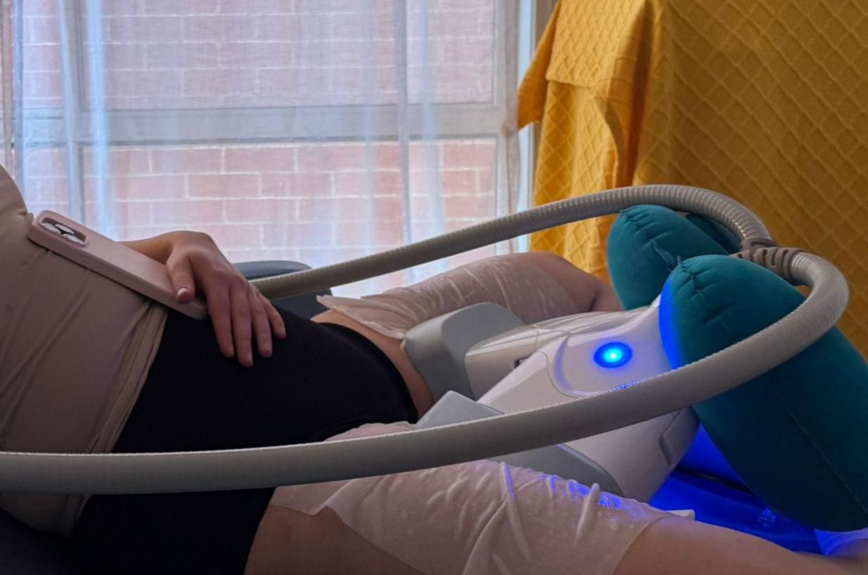 A client resting on a treatment bed during a cryolipolysis session, with cooling applicators positioned on the upper leg.
